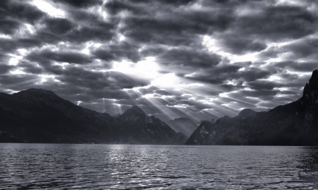 Ein schwarz-weisses Bild von einem See mit Bergen im Hintergrund